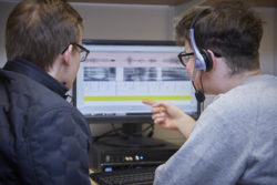 Students looking at a computer displaying an acoustic representation of speech.
